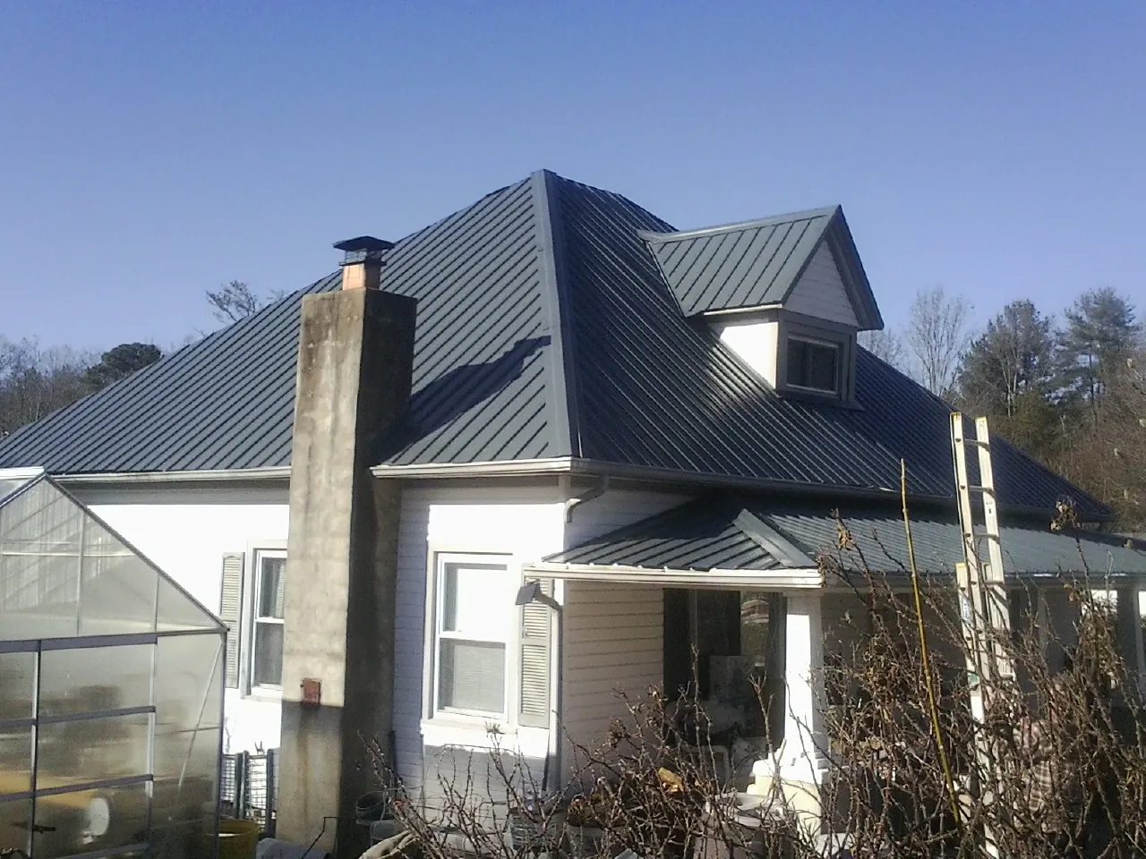 Dark blue standing seam metal roof on a white farmhouse with dormer — Slate & Tile Roof Repair by Roofing Brothers in Mount Sherman