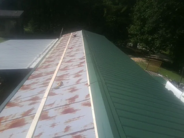 Old rusted panels beside newly installed green metal roofing — Wind Damage Roof Repair by Roofing Brothers in Mount Sherman