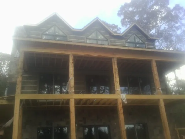 Dormers and porch framing on a large log home under construction — Roof Coating work by our crew in Mount Sherman