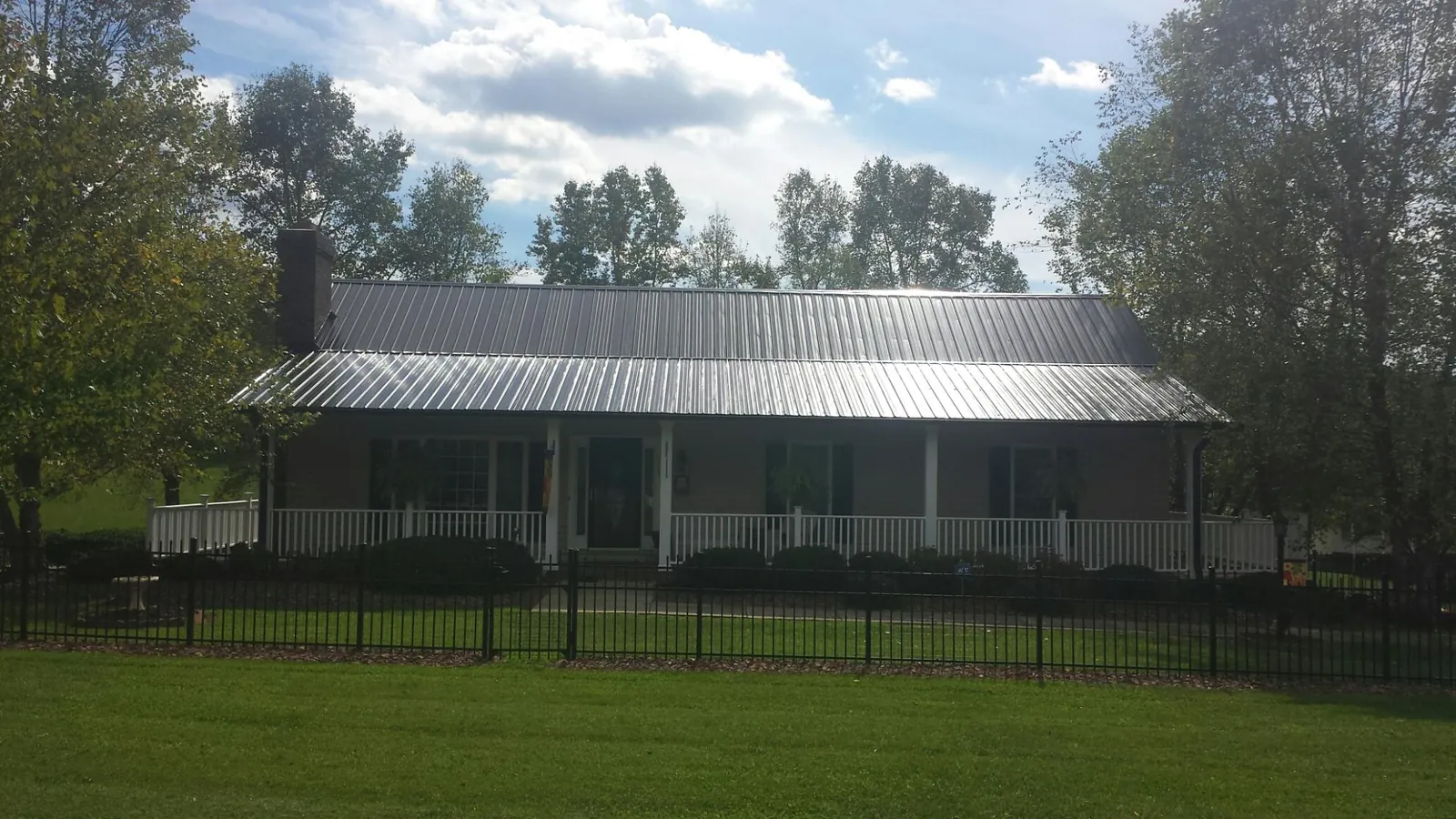 Gray metal roof on a brick ranch with a full width front porch — Gutter Guard Installation work by our crew in Mount Sherman