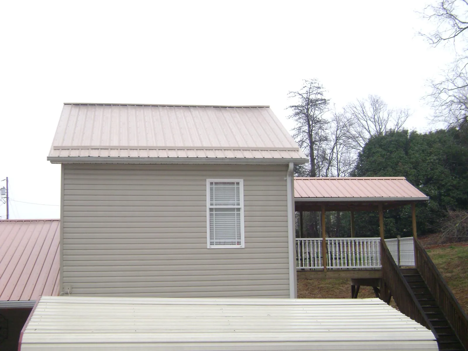 Tan metal roofs on a two story addition and attached porch, from a Roof Replacement job in Mount Sherman