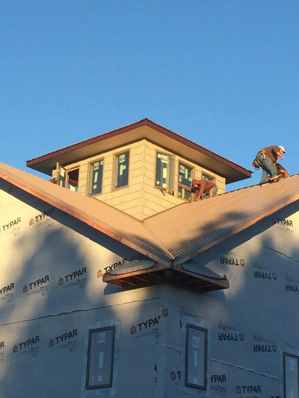 Roofers working around a rooftop cupola on a new metal roof at sunset — Roof Waterproofing in Mount Sherman by Roofing Brothers
